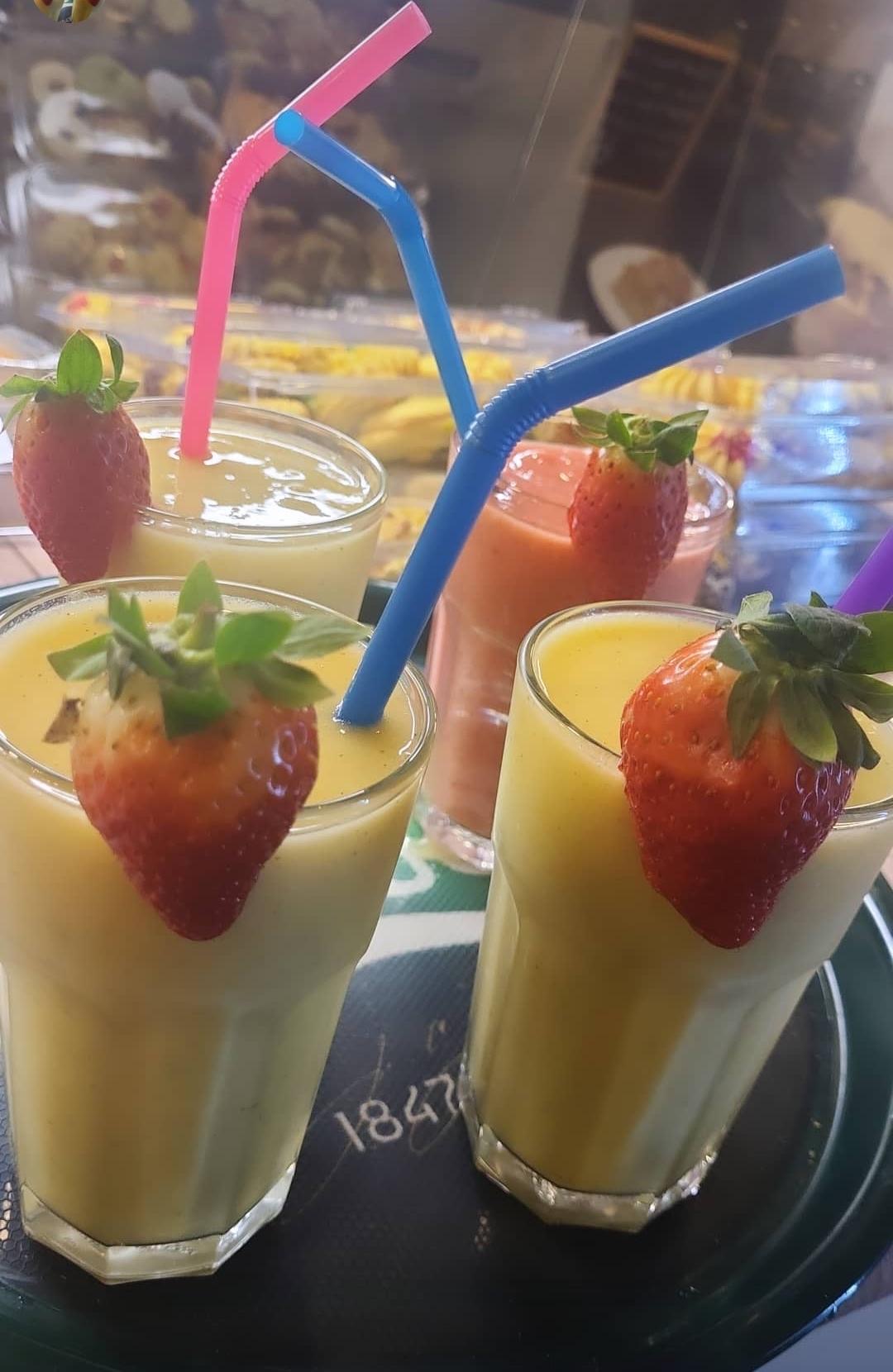 Frische Mango- und Erdbeer-Smoothies mit Erdbeeren am Glasrand